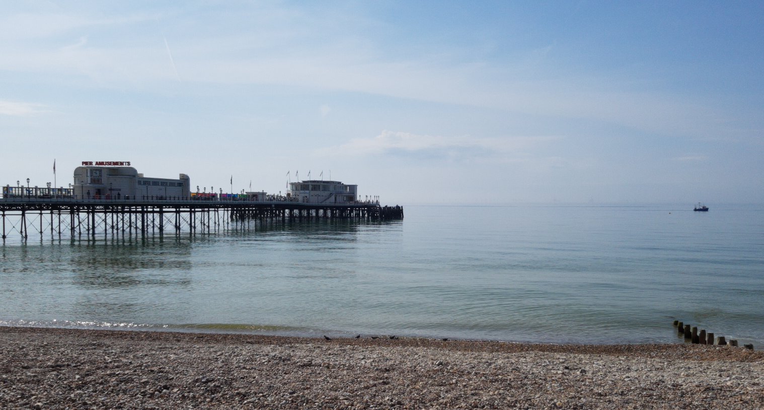 the sea with pier on left and boat on right